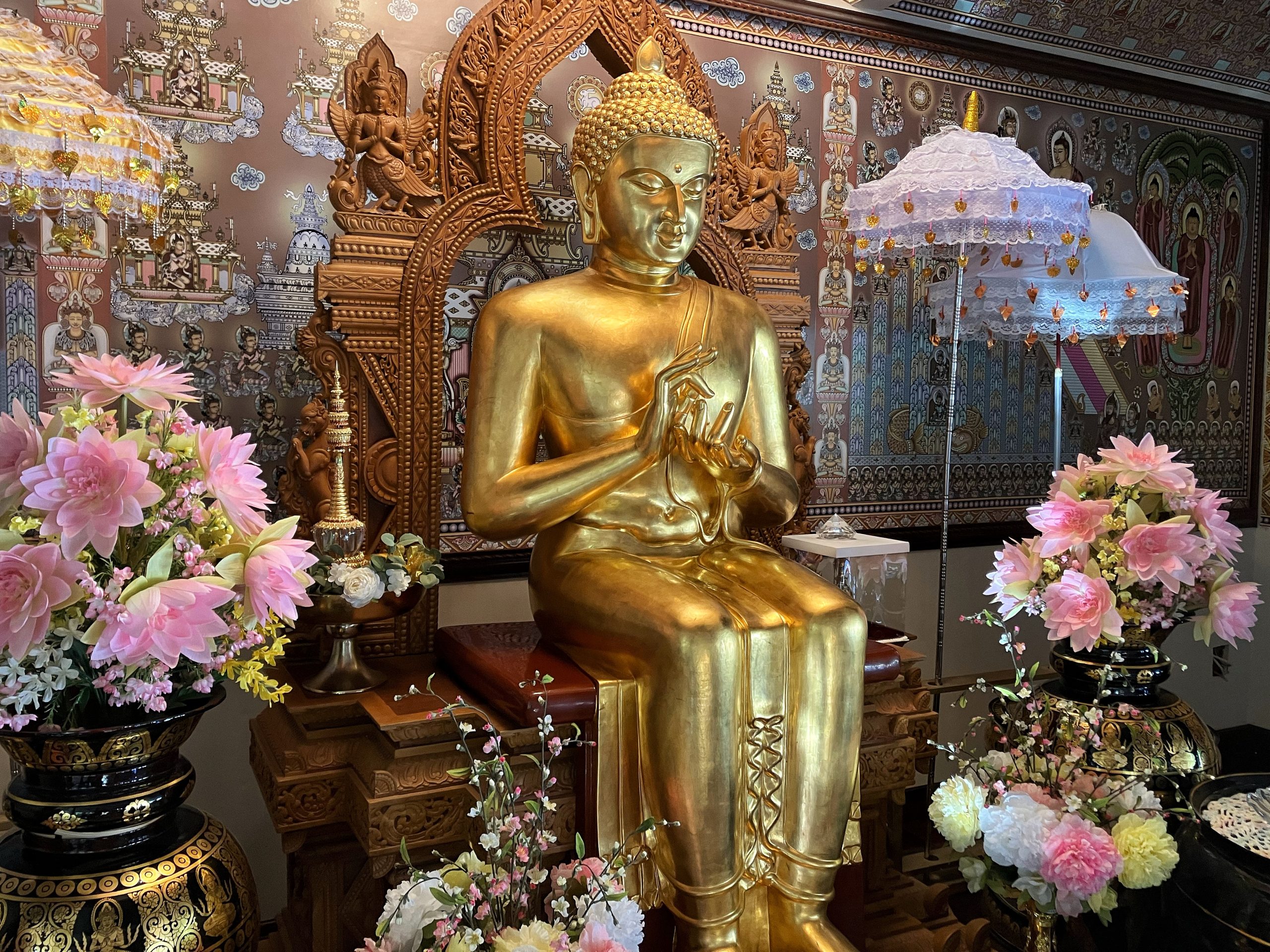 Large seated Buddha statue surrounded by flowers